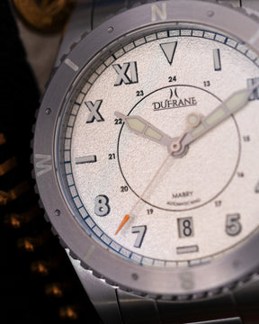 Close-up of a Dufrane watch with a white face and silver case.